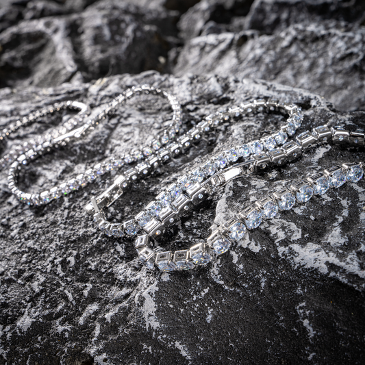 Set of tennis bracelets with clear stones, close-up on dark rock
