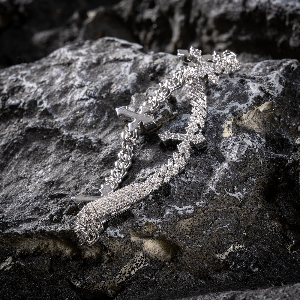 White gold cross Cuban link bracelet with dangling cross charm and jeweled chain links, close-up